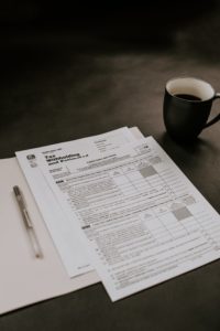withholding tax reports beside a black ceramic mug